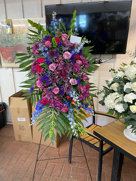 Easel spray for a funeral with dark purple and blue flowers.