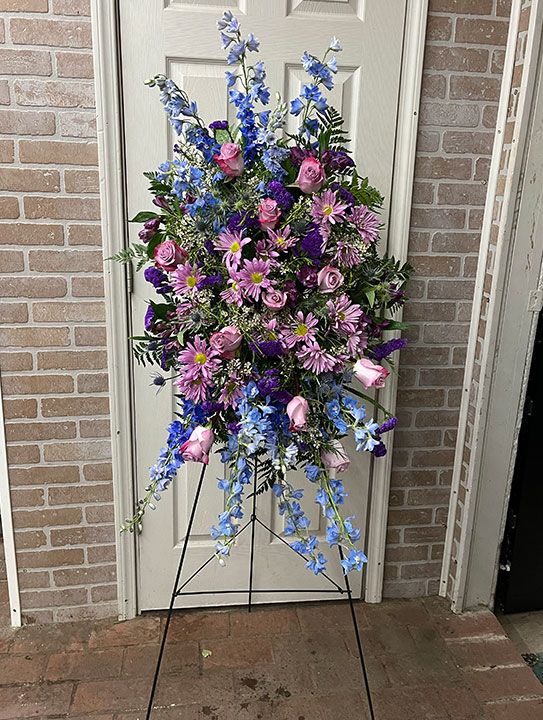 Easel spray for a funeral with purple and blue flowers.