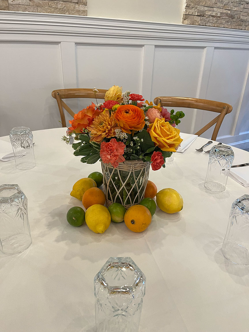 Table flower arrangement with citrus fruit.