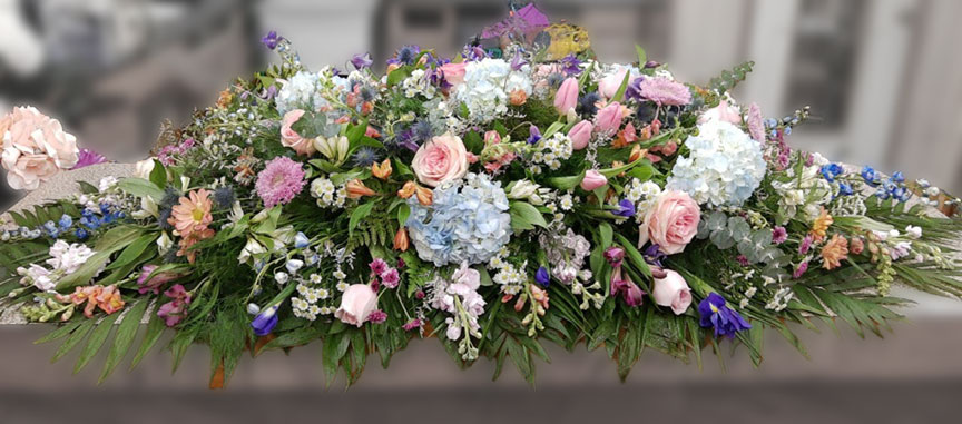Casket spray with pastel watercolor flowers.