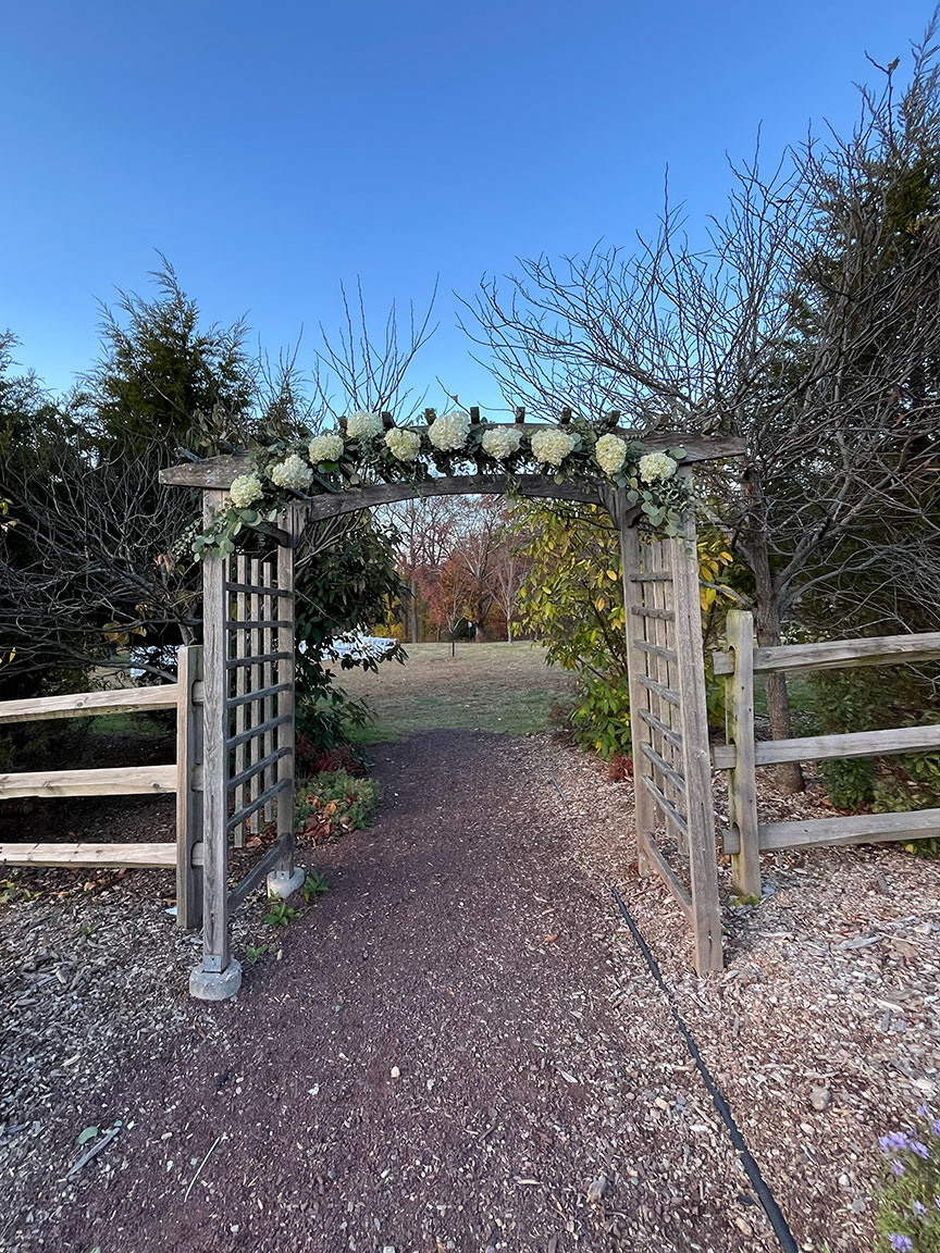 Outside wooden arch decorated with wedding flowers.