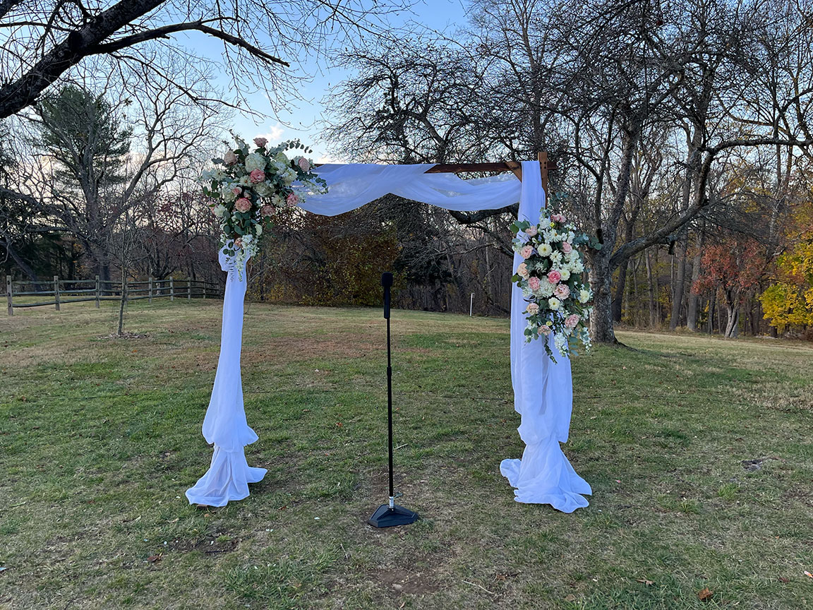 Outdoor wedding arch, decorated with flowers.